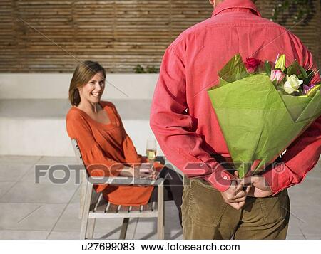 Stock Image - Man hiding flowers behind back. Fotosearch