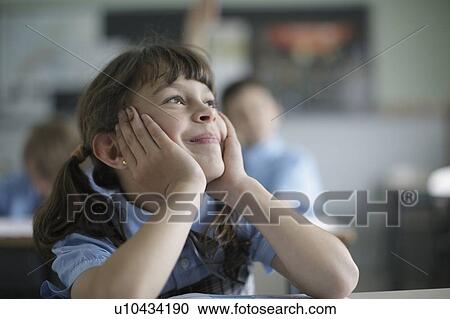 Stock Image - School girl daydreaming in class. Fotosearch