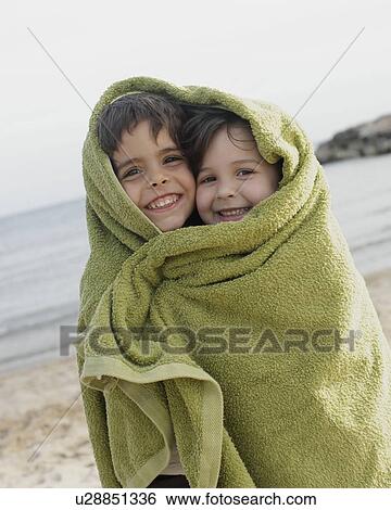 Stock Photograph - Two young children in towel on beach. Fotosearch