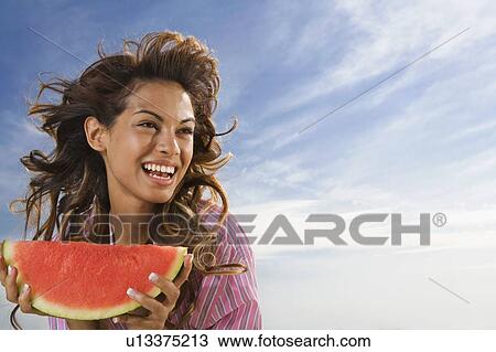 Woman laughing and eating watermelon outdoors. View Large Photo Image Stock Image - Woman laughing and eating watermelon outdoors.. Fotosearch