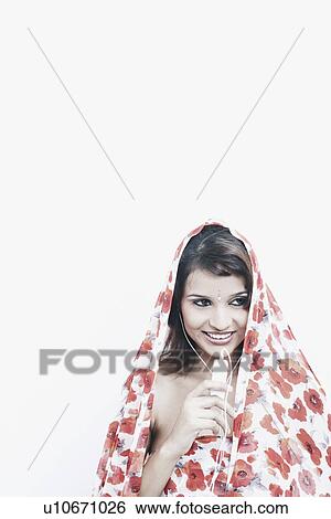 Close-up of a young woman with a stole on her head listening to an MP3 player View Large Photo Image Stock Photograph - Close-up of a young woman with a stole on her head listening to an MP3 player. Fotosearch