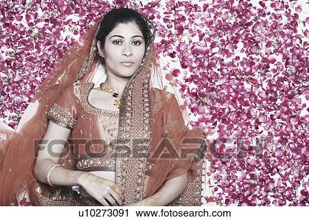 Stock Image - High angle view of a young woman lying on rose petals. Fotosearch