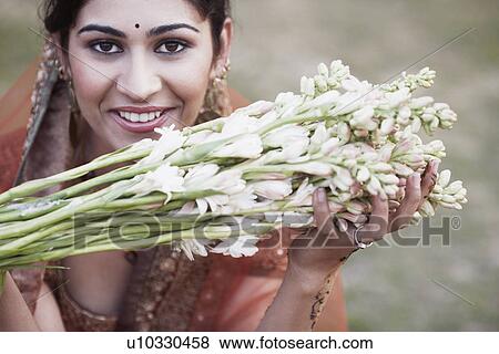 Stock Photo - Portrait of a young woman holding a bunch of flowers. Fotosearch