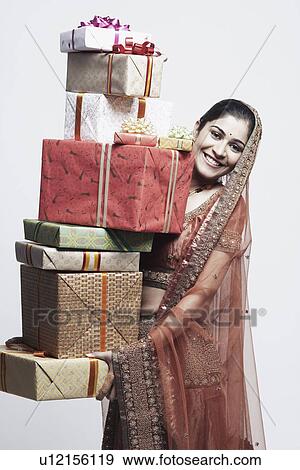 Stock Photo - Portrait of a young woman holding a stack of gifts. Fotosearch