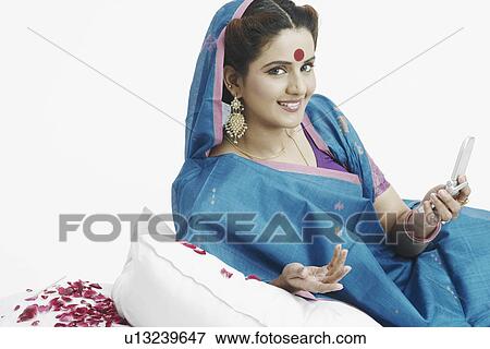 Portrait of a young woman holding a mobile phone View Large Photo Image Stock Photo - Portrait of a young woman holding a mobile phone. Fotosearch