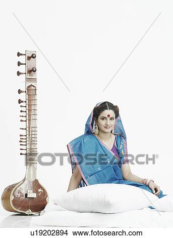 Picture - Portrait of a young woman sitting near a sitar. Fotosearch