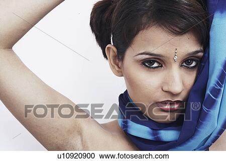 Stock Image - Portrait of a young woman standing with her hand raised. Fotosearch