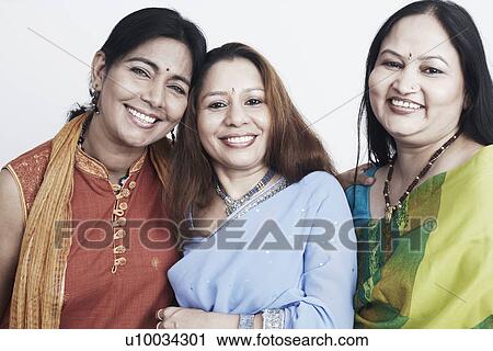 Stock Image - Portrait of two mature women and a mid adult woman smiling. Fotosearch