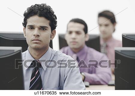 Businessmen working on computers in an office View Large Photo Image Stock Photography - Businessmen working on computers in an office. Fotosearch
