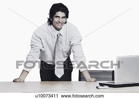 Stock Image - Portrait of a businessman bending over the table. Fotosearch
