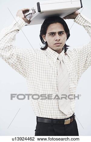 Stock Image - Portrait of a businessman carrying a briefcase on his head. Fotosearch