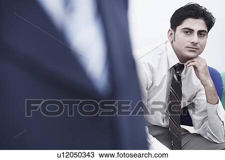 Stock Image - Portrait of a businessman thinking with his hand under his chin. Fotosearch