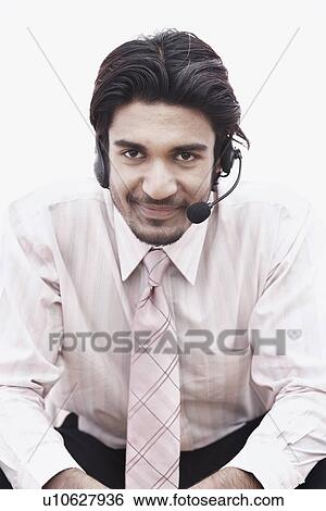 Stock Photograph - Portrait of a businessman wearing a hands free device. Fotosearch