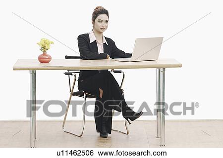 Stock Photograph - Portrait of a businesswoman sitting in an office with her legs crossed. Fotosearch