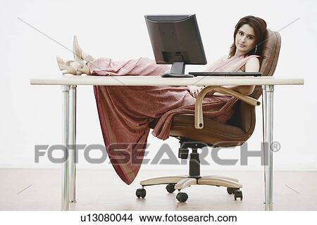 Picture - Portrait of a businesswoman with her feet up on the table. Fotosearch