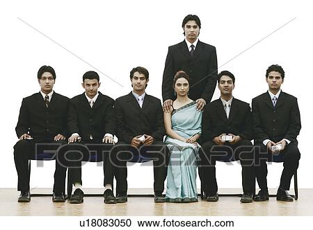 Stock Image - Portrait of a young woman sitting between a group of young men. Fotosearch