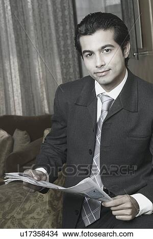 Picture - Close-up of a businessman holding a newspaper. Fotosearch
