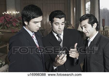 Close-up of three businessmen looking at a mobile phone View Large Photo Image Stock Photo - Close-up of three businessmen looking at a mobile phone. Fotosearch