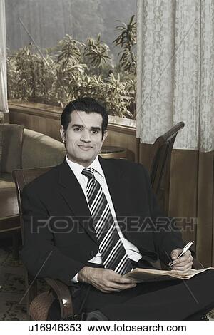 Stock Image - Portrait of a businessman holding a newspaper. Fotosearch