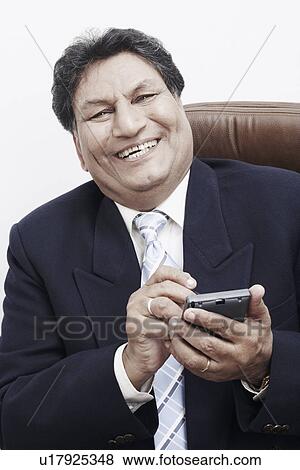 Stock Photo - Portrait of a businessman operating a personal data assistant. Fotosearch