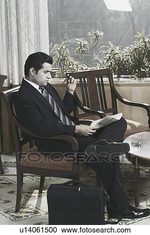 Stock Image - Side profile of a businessman reading a newspaper. Fotosearch