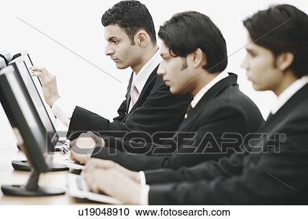 Side profile of three businessmen working on computers in an office View Large Photo Image Stock Image - Side profile of three businessmen working on computers in an office. Fotosearch