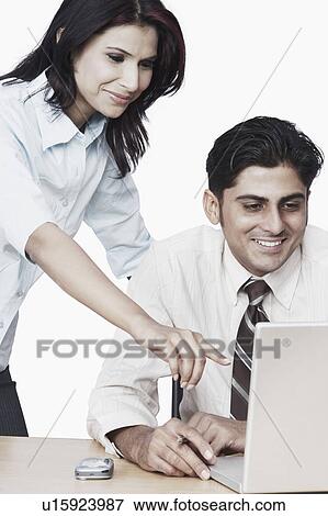 Stock Photo - Businessman and a businesswoman using a laptop. Fotosearch