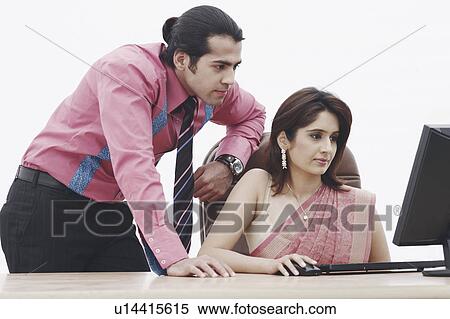 Stock Photography - Close-up of a businesswoman and a businessman looking at a computer monitor. Fotosearch