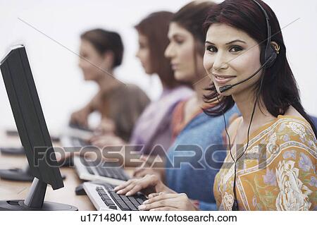 Stock Image - Close-up of four businesswomen sitting in front of computers. Fotosearch