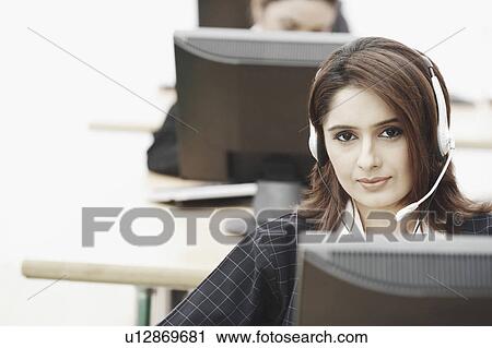 Portrait of a businesswoman wearing a headset sitting in front of a computer View Large Photo Image Stock Image - Portrait of a businesswoman wearing a headset sitting in front of a computer. Fotosearch