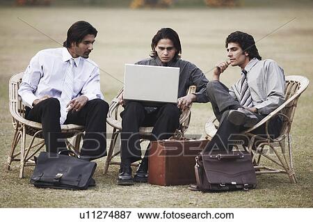 Stock Photo - Three businessmen using a laptop. Fotosearch