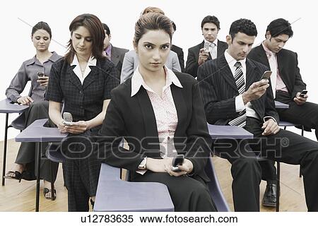 Business executives sitting on chairs holding mobile phones View Large Photo Image Stock Photography - Business executives sitting on chairs holding mobile phones. Fotosearch
