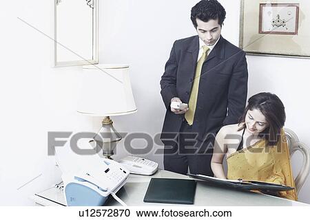 Businessman and a businesswoman reading documents in an office View Large Photo Image Stock Image - Businessman and a businesswoman reading documents in an office. Fotosearch