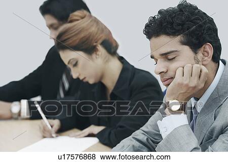 Stock Photo - Businessman sitting in a conference room with his eyes closed. Fotosearch