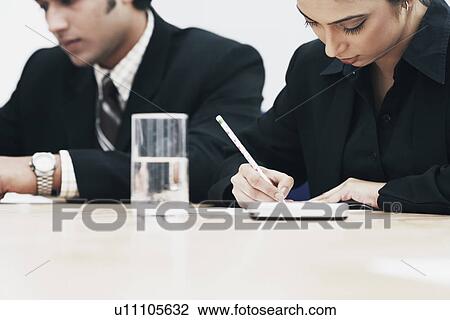 Businesswoman and a businessman sitting in a conference room View Large Photo Image Stock Image - Businesswoman and a businessman sitting in a conference room. Fotosearch