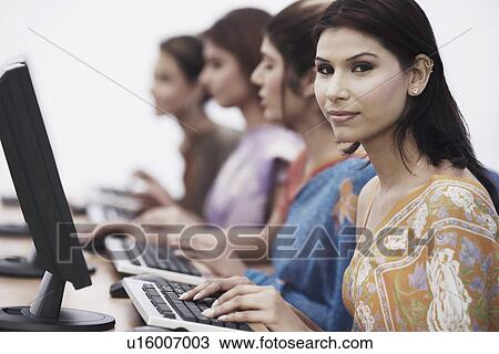 Stock Image - Close-up of four businesswomen sitting in front of computers. Fotosearch