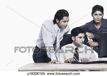 Stock Photography - Two businessmen and a businesswoman looking at a computer. Fotosearch