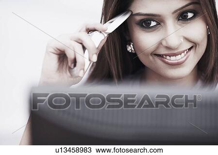 Stock Image - Close-up of a businesswoman smiling and holding a mobile phone. Fotosearch