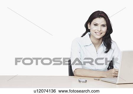 Stock Photograph - Portrait of a businesswoman smiling in front of a laptop. Fotosearch