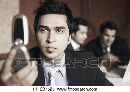 Close-up of a businessman looking at a mobile phone View Large Photo Image Stock Photography - Close-up of a businessman looking at a mobile phone. Fotosearch