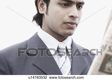 Stock Image - Close-up of a businessman reading a newspaper. Fotosearch