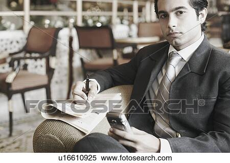 Portrait of a businessman holding a mobile phone View Large Photo Image Stock Photography - Portrait of a businessman holding a mobile phone. Fotosearch