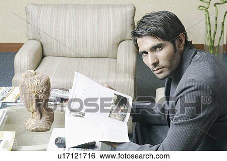 Stock Photograph - Portrait of a businessman reading a magazine. Fotosearch