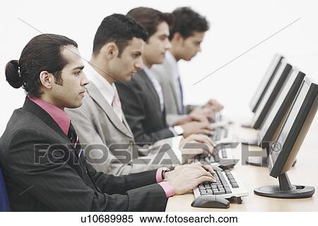 Stock Photography - Side profile of four businessmen sitting in front of computers. Fotosearch