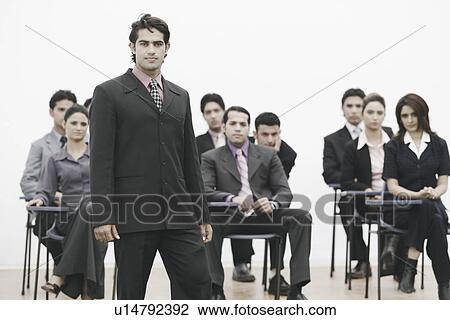 Portrait of a businessman standing in front of business executives View Large Photo Image Stock Image - Portrait of a businessman standing in front of business executives. Fotosearch