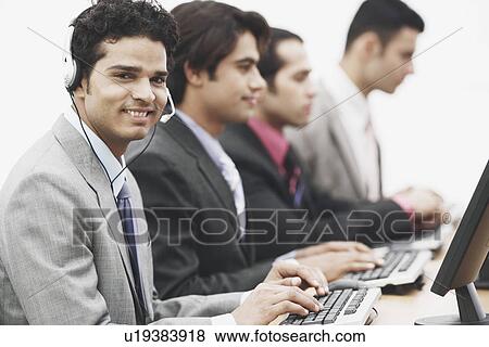 Stock Photo - Portrait of a businessman wearing a headset sitting in front of a computer. Fotosearch