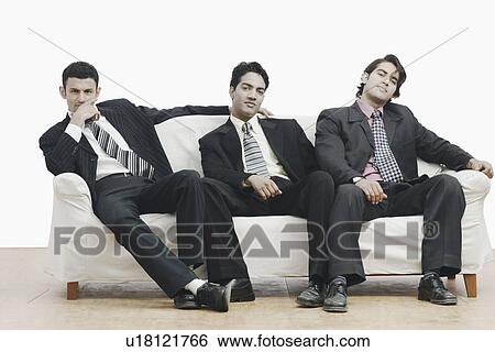 Stock Photograph - Portrait of three businessmen sitting on a couch. Fotosearch