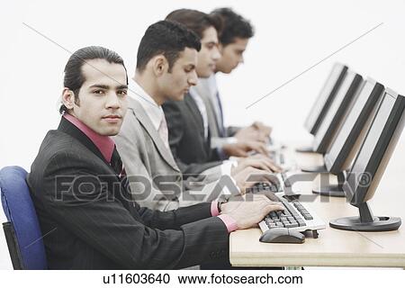 Side profile of four businessmen sitting in front of computers View Large Photo Image Stock Image - Side profile of four businessmen sitting in front of computers. Fotosearch