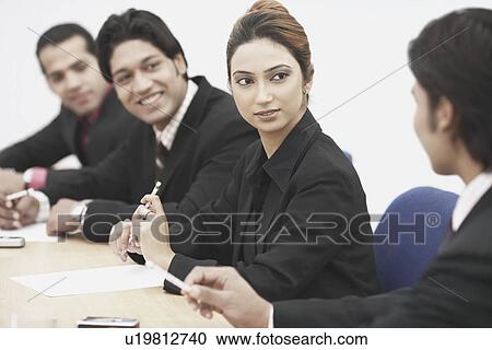 Stock Image - Three businessmen and a businesswoman sitting in a meeting. Fotosearch