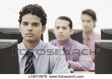 Businessmen working on computers in an office View Large Photo Image Stock Photograph - Businessmen working on computers in an office. Fotosearch
